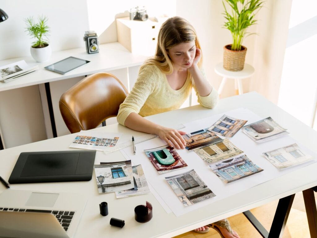 Woman reviewing printed photos at a desk.