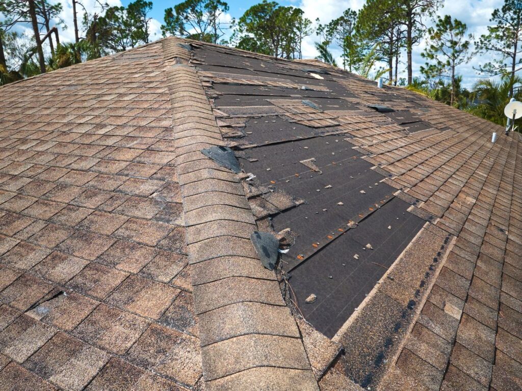 Damaged shingles on a rooftop, exposing the underlayment.