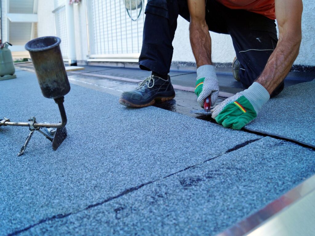 A man with gloves repairing the roof.