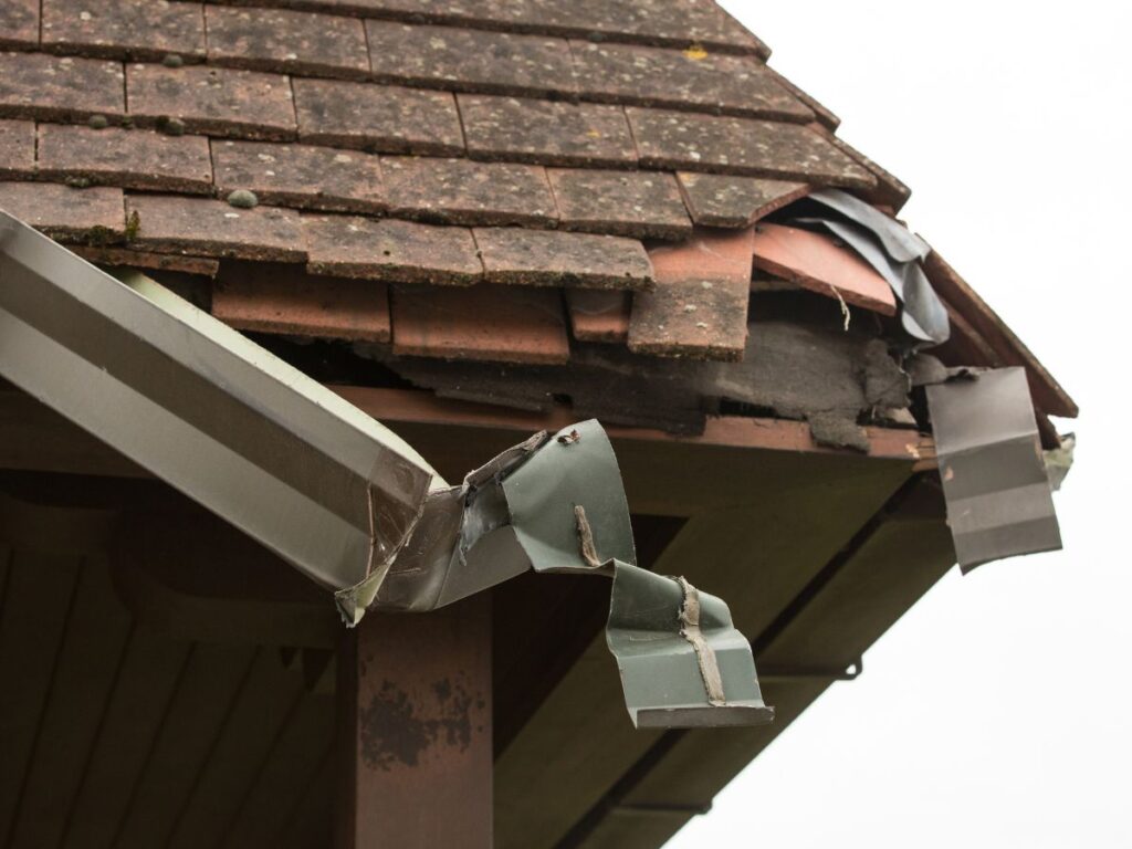 Damaged gutter with cracks and bent sections on an old roof.