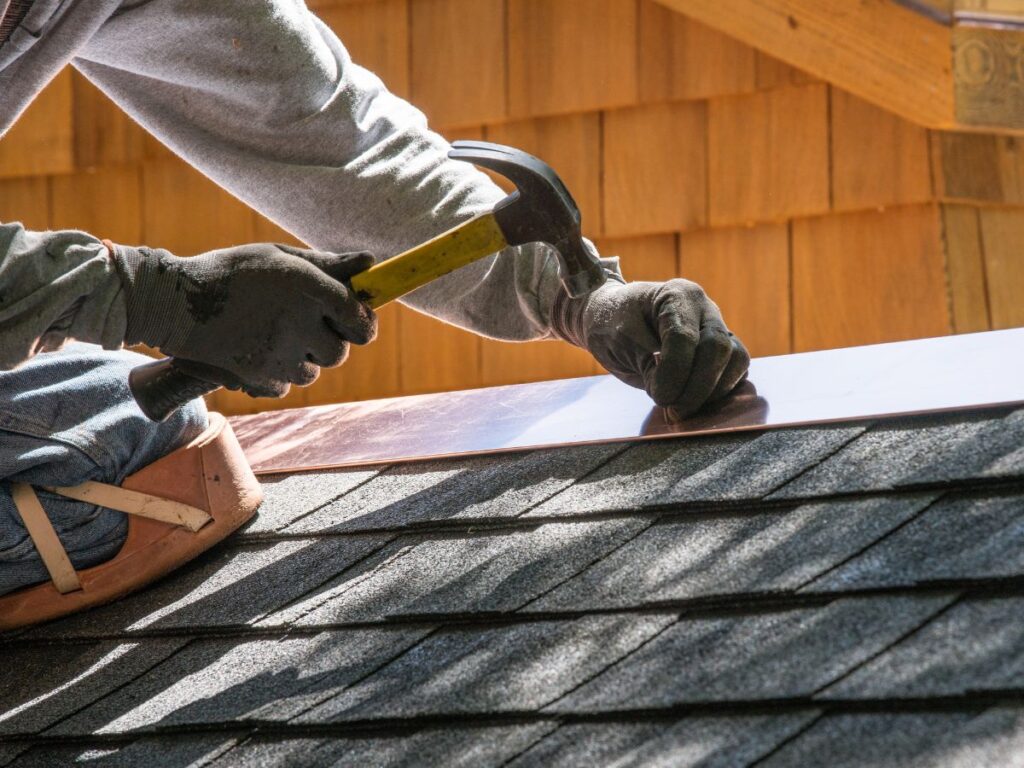 Roofer hammering a piece of flashing into place.