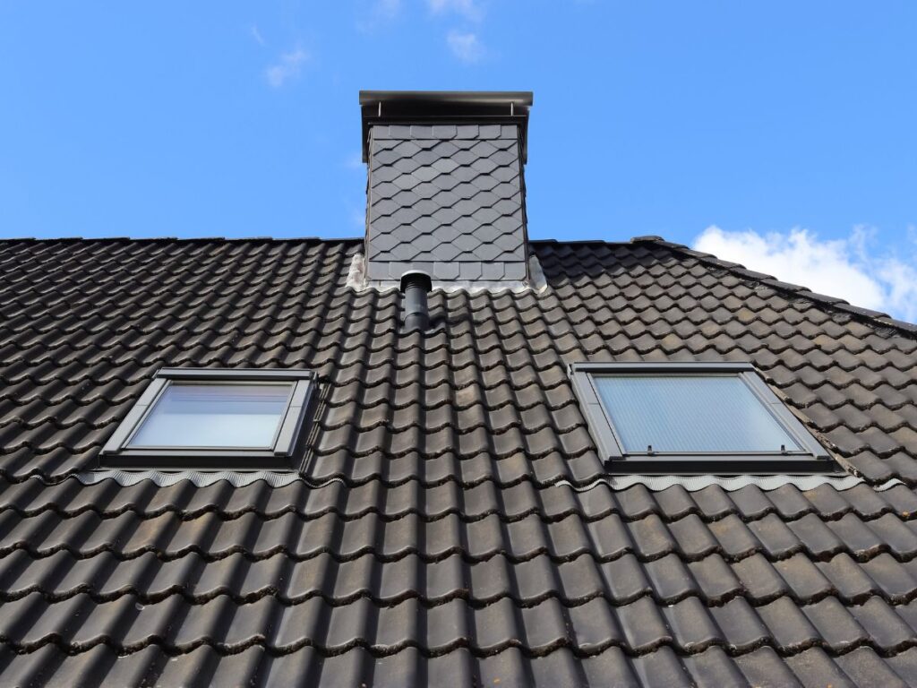 Black roof with two skylights and a chimney.