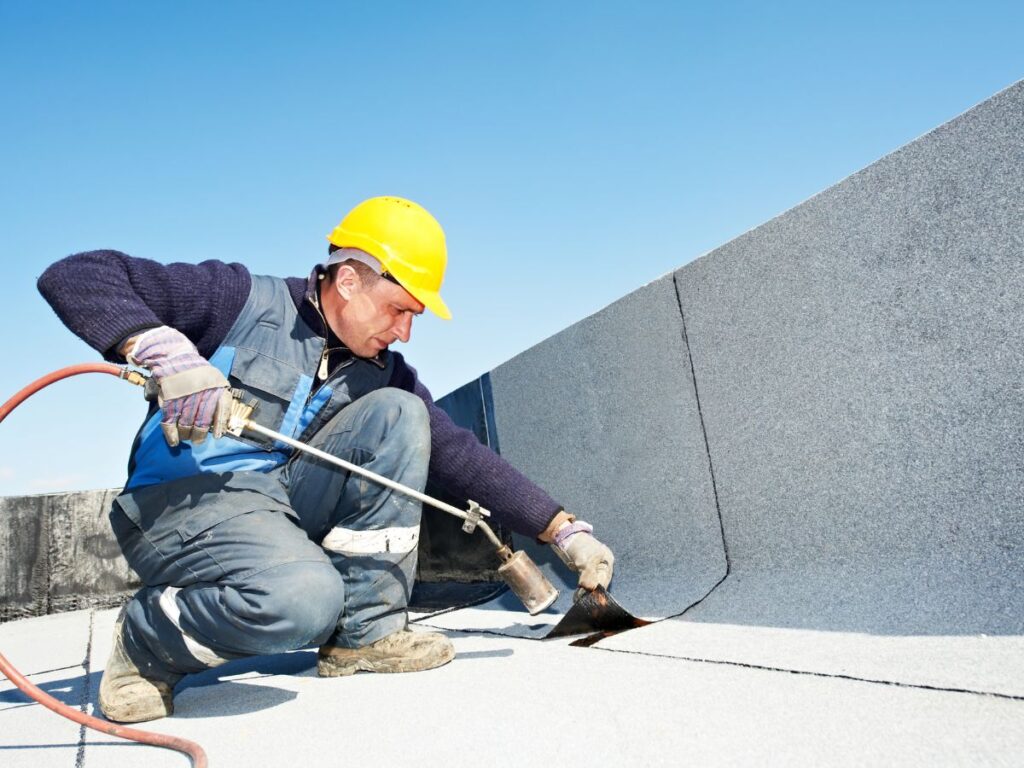 A man waearing a yellow hardhat repairing something.