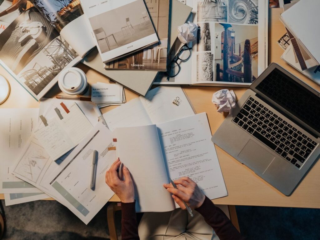 A woman on an office table opening a note book and trying to write in it.