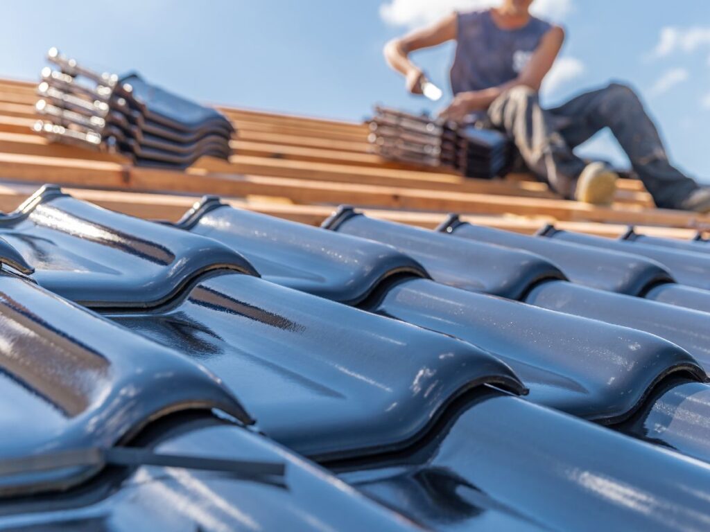 Close-up of glossy black roof tiles being installed.