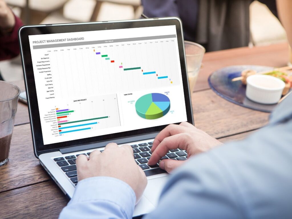 A man using a laptop displaying different graphs.