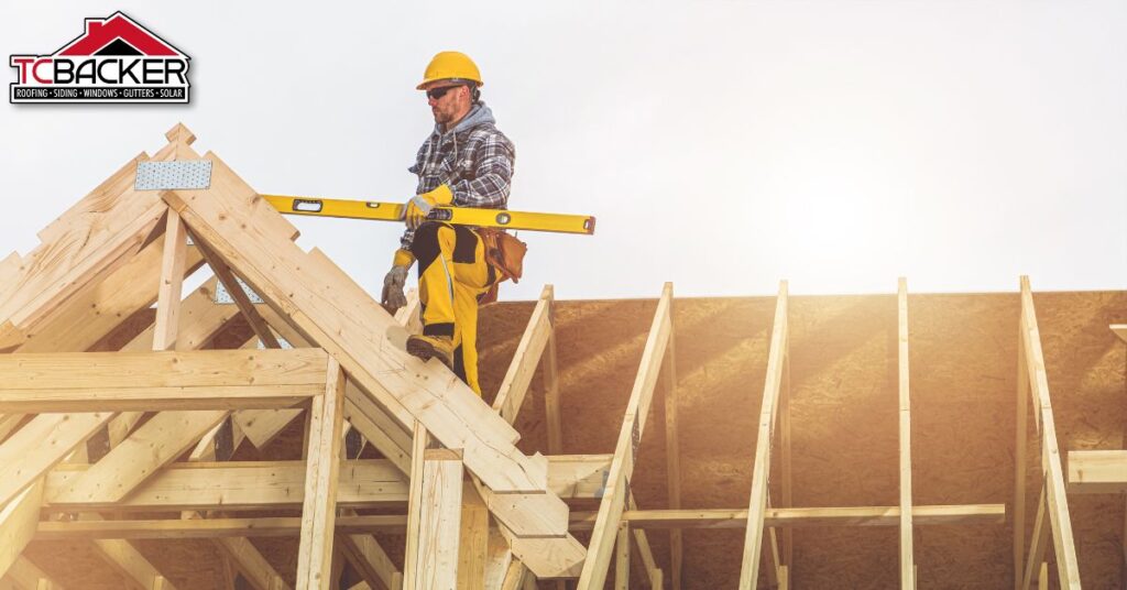 A man wearing a complete safety gear standing on the framing of the roof.