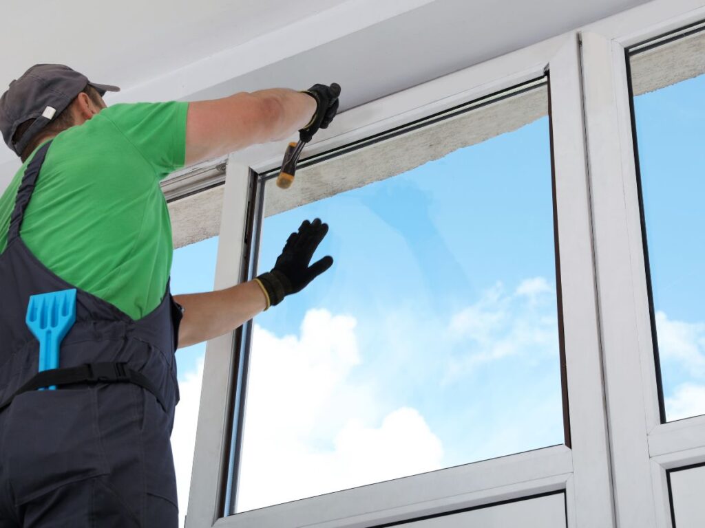 Worker hammering during a window installation.