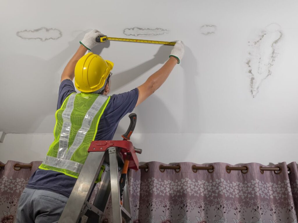 Inspector measuring water damage on a ceiling.