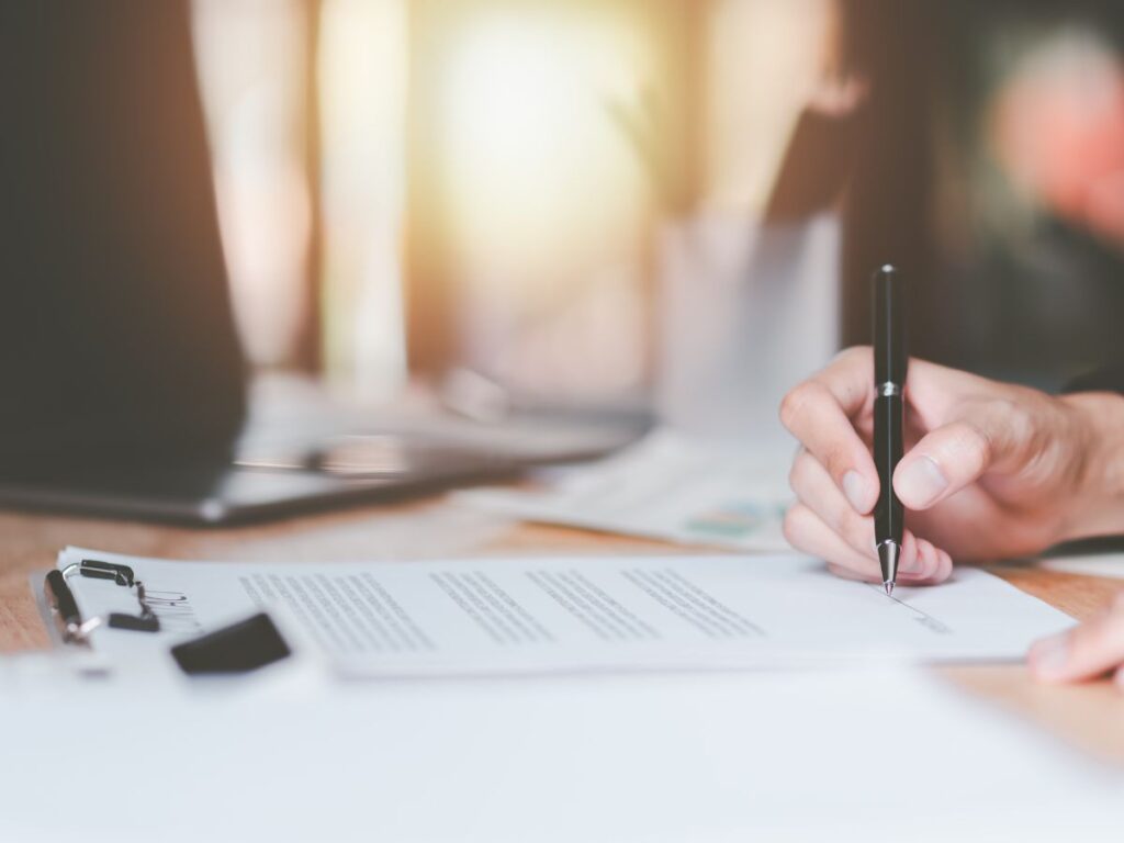 A person signing a contract with a pen.