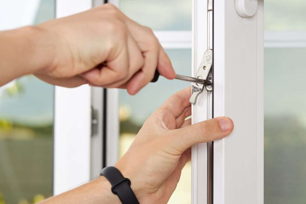 best replacement windows handyman adjusting white pvc plastic window indoors. worker using screwdriver to repair upvc window. homework maintenance.